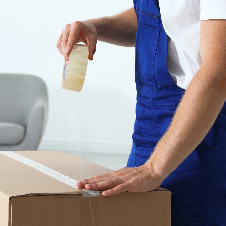 Moving service employee sealing cardboard box  Moving service employee